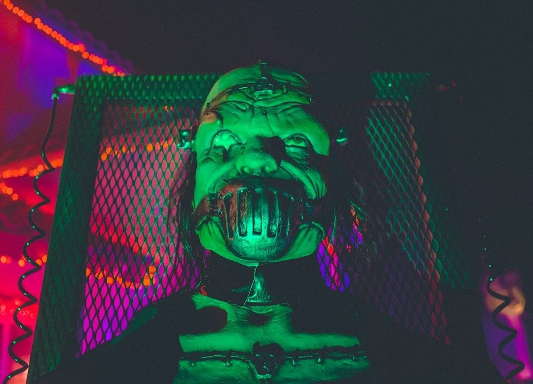 Grün beleuchtete Horrorfigur mit Metallmaske vor einem Sci-Fi-Gitter